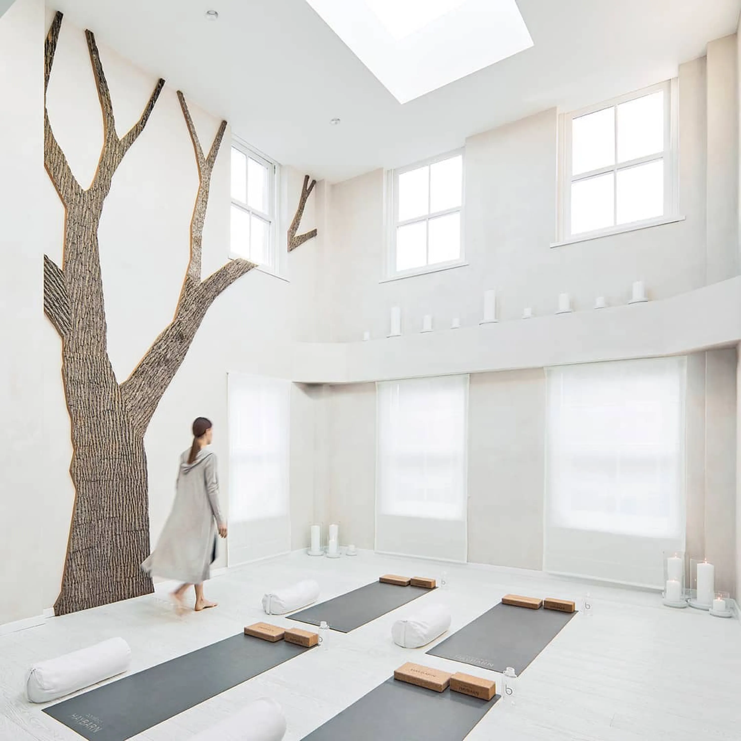 Total white meditation room with a tree-shaped portion of the wall covered with real bark.