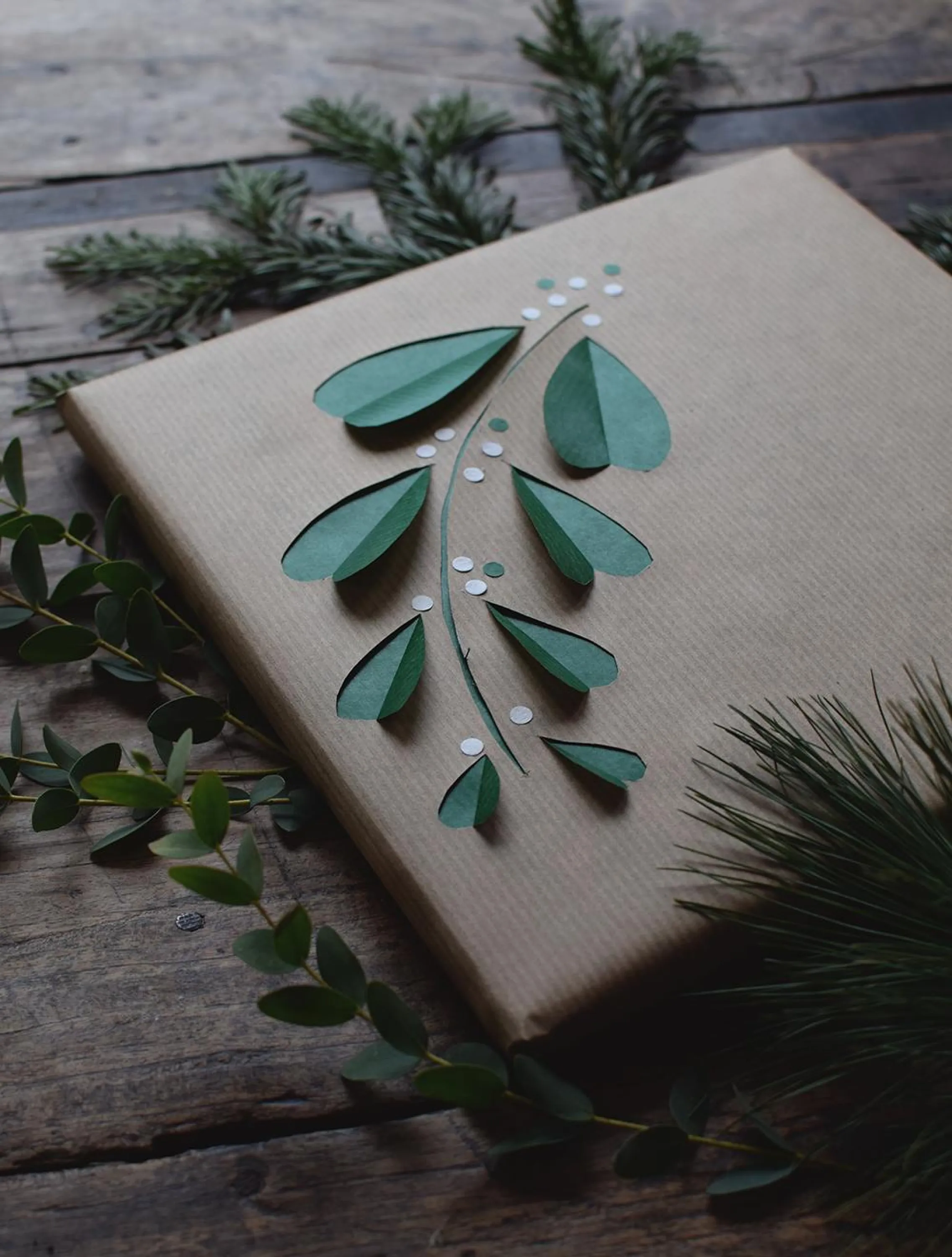 Greena and brown wrapping paper decorated with a cut-off in the shape of mistetoe.