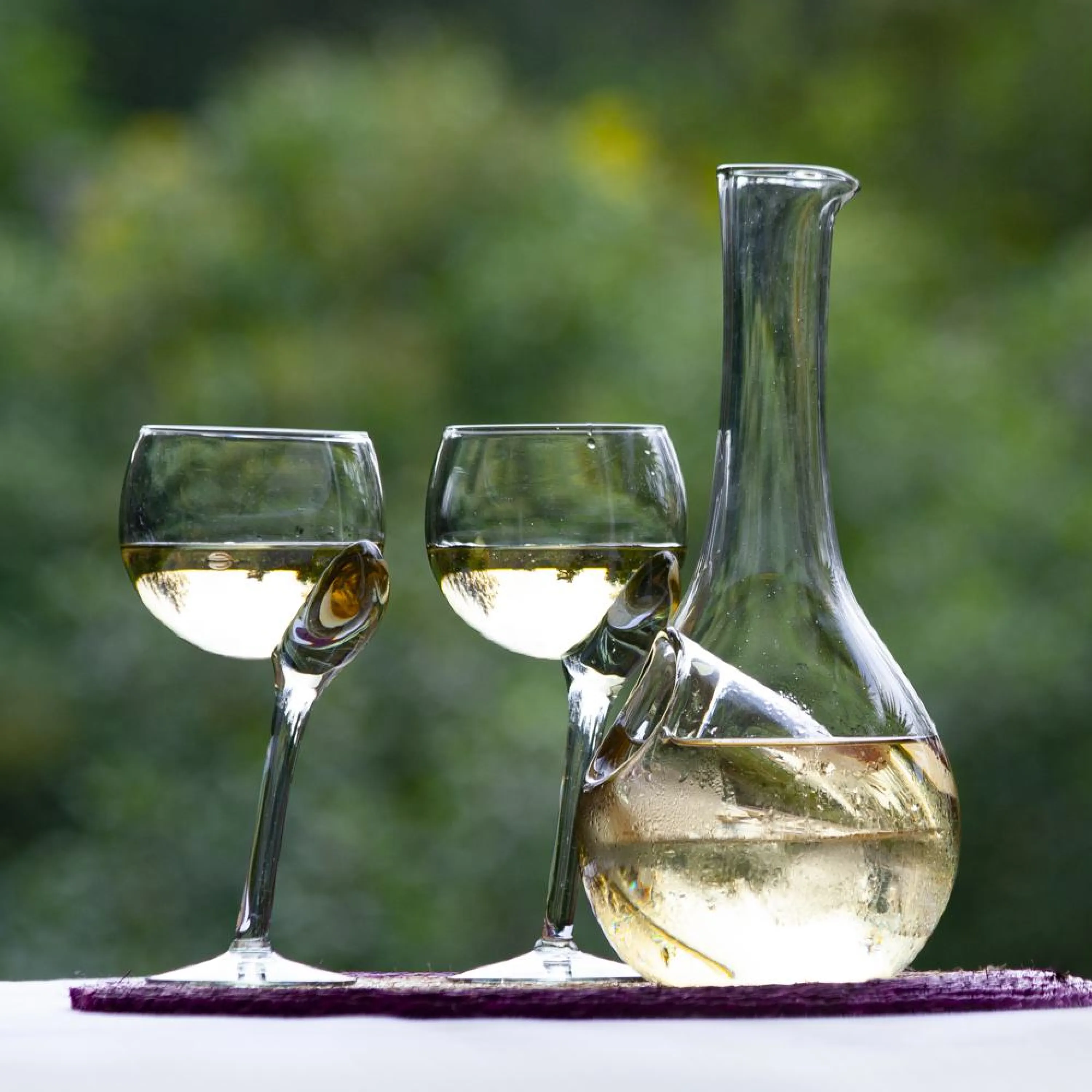 Recycled glass decanter with two half-full glasses.