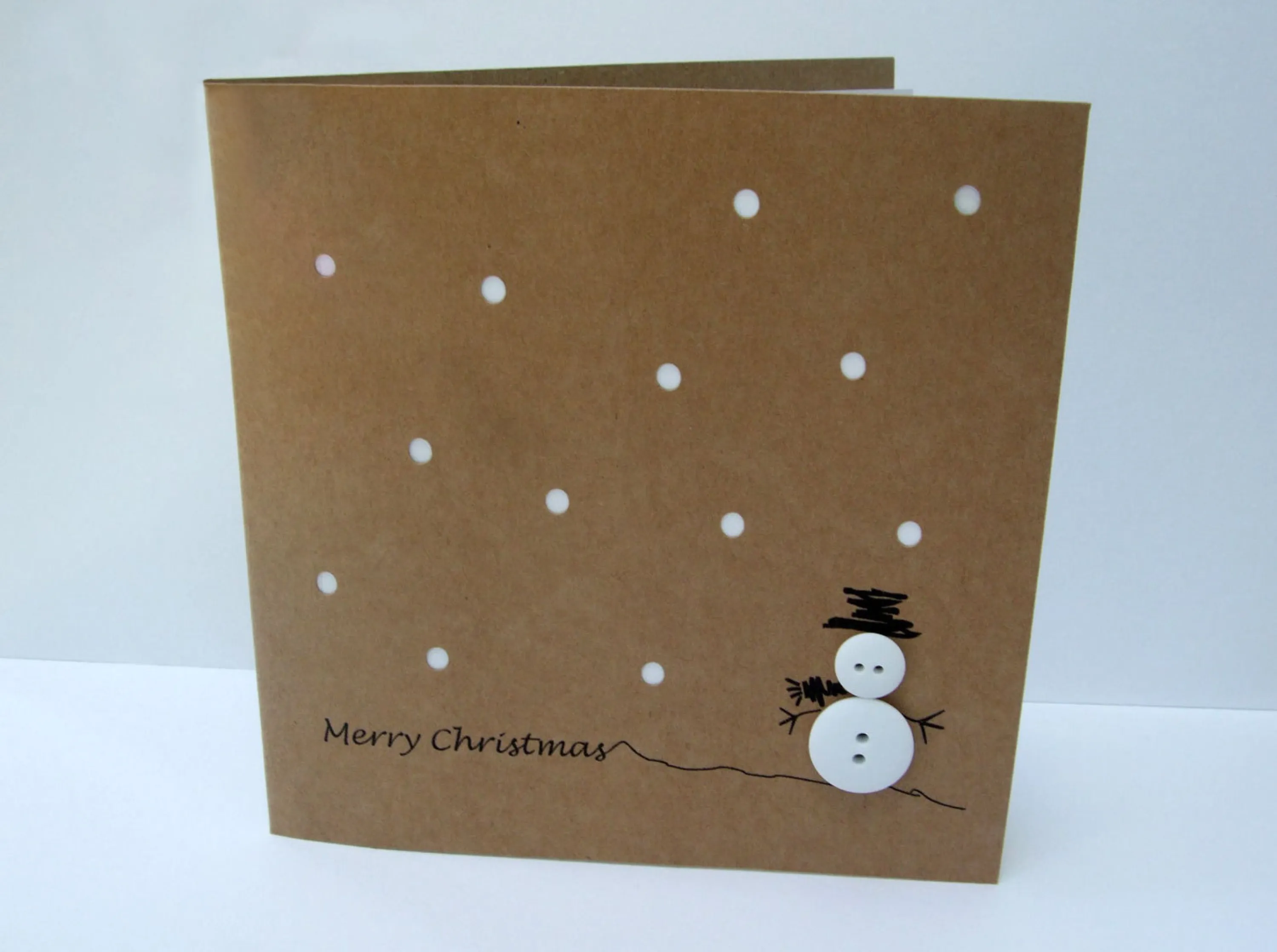 Christmas card with two white buttons representing the body of a snowman and the hat drawn with black pen.