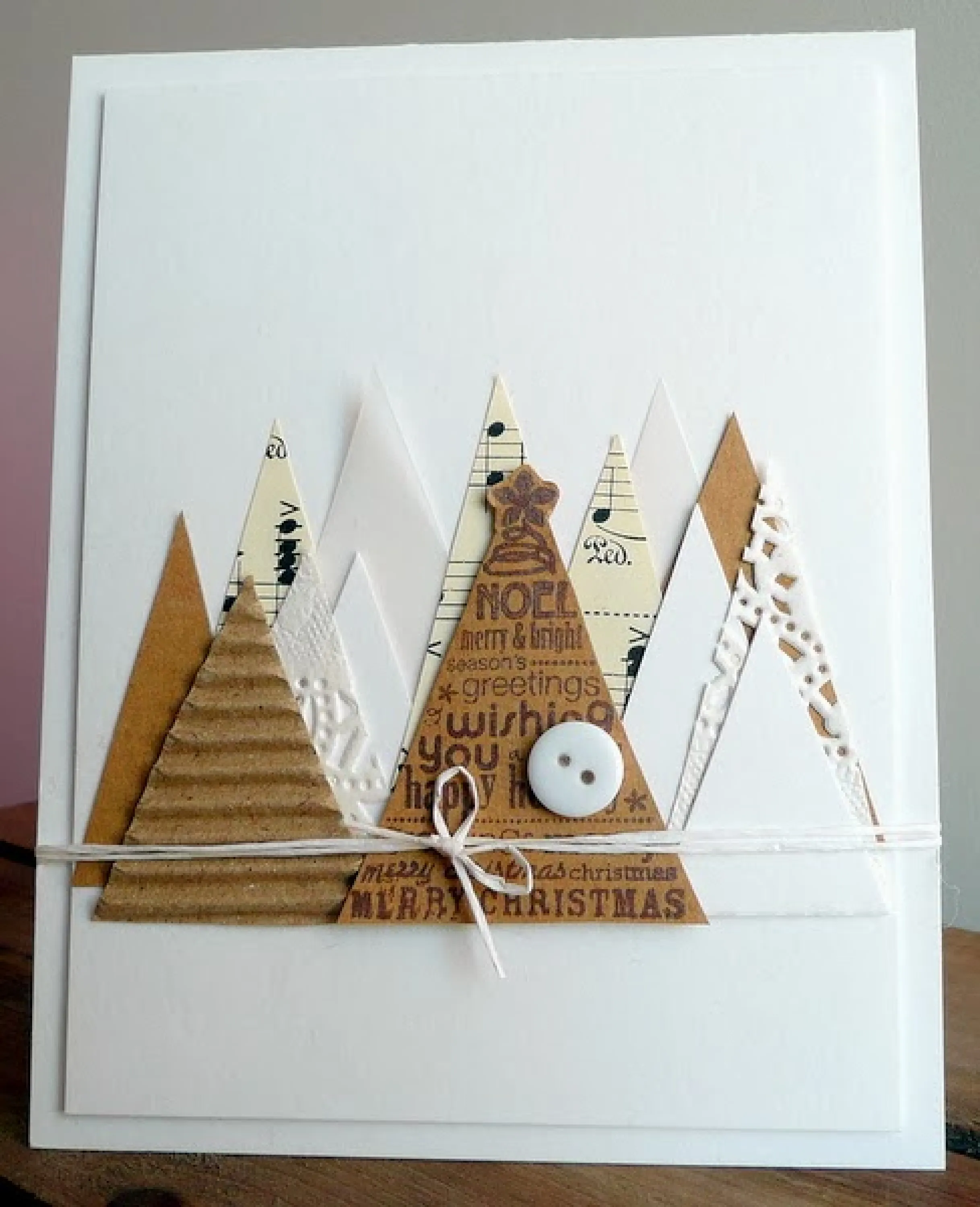 White Christmas card decorated with triangular cut-outs representing Christmas trees.