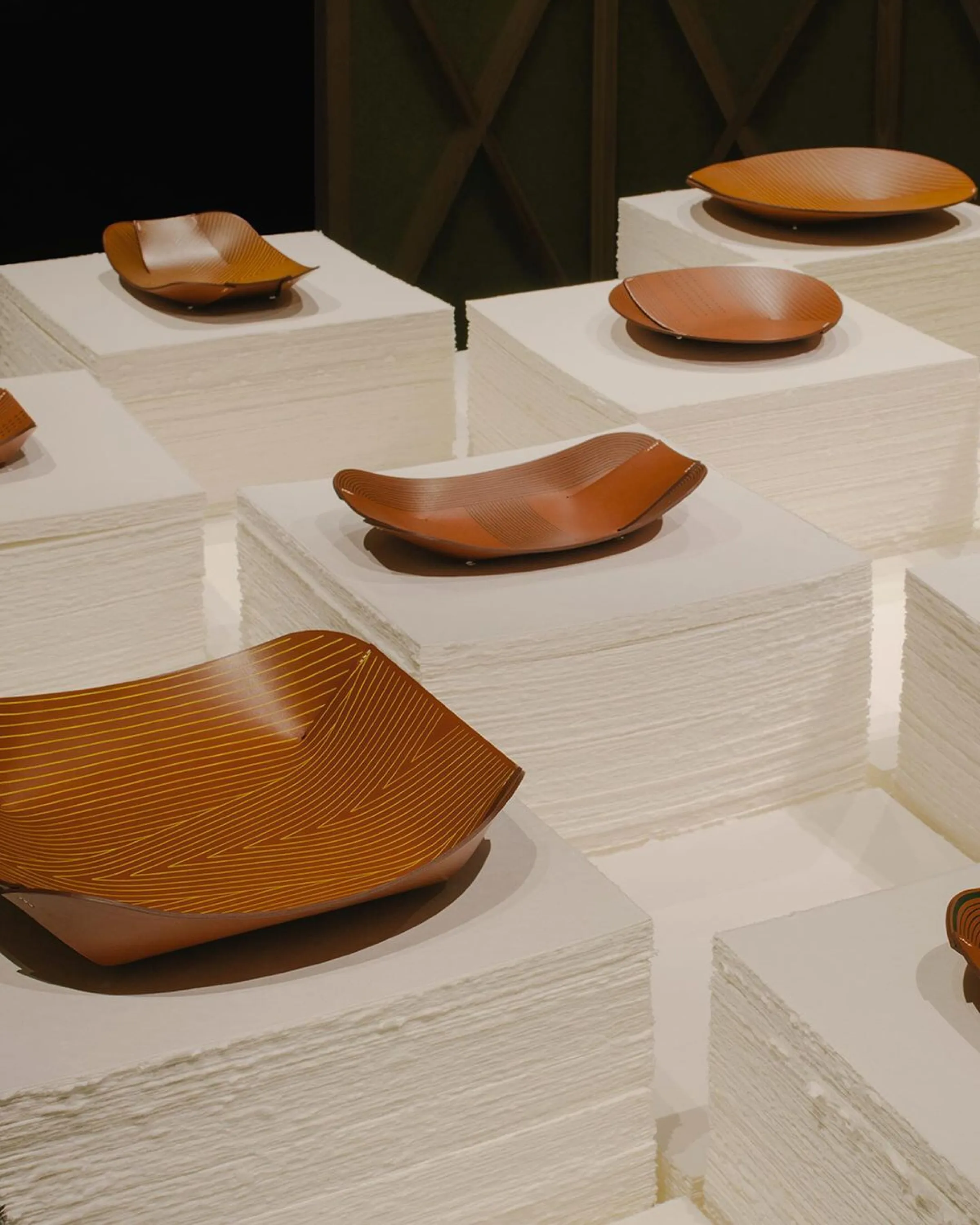 Bowls and vessels displyed on piles of paper sheets.