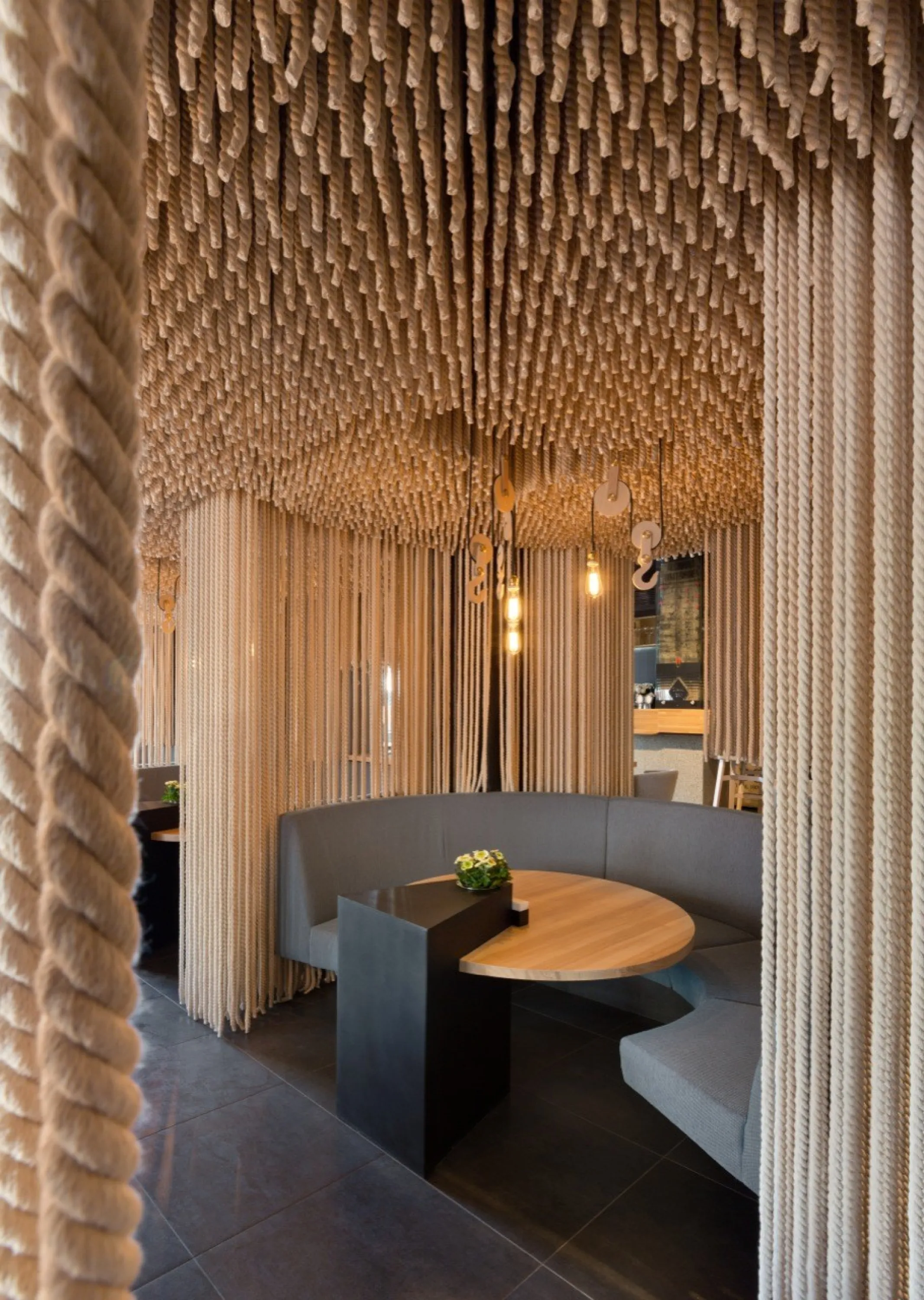 Restaurant tables separated with ropes hanging from the ceiling.