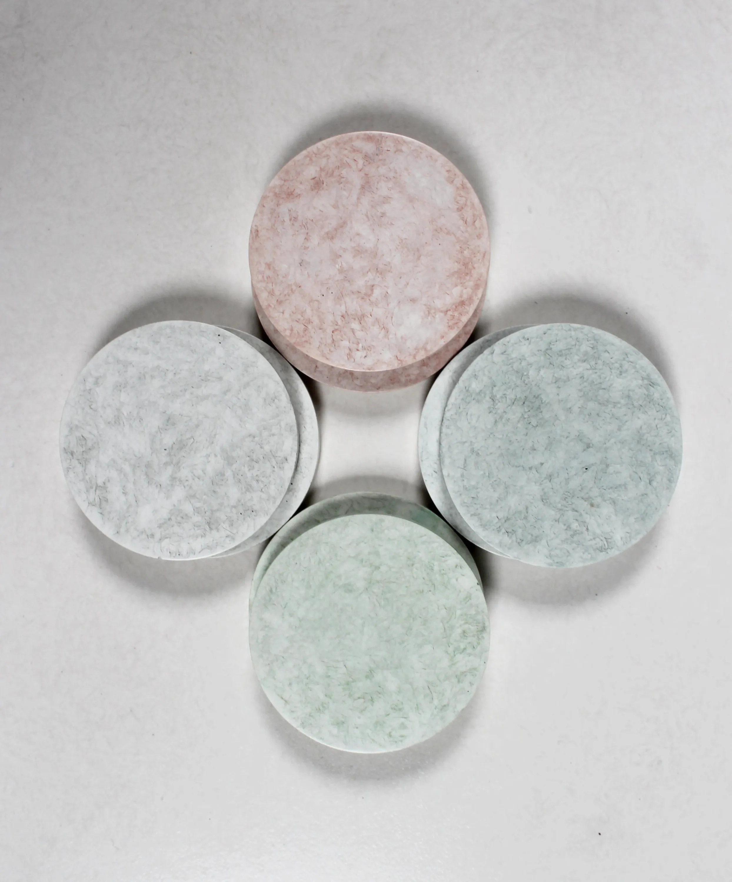 Flatlay of pastel-coloured coasters made with jute waste.