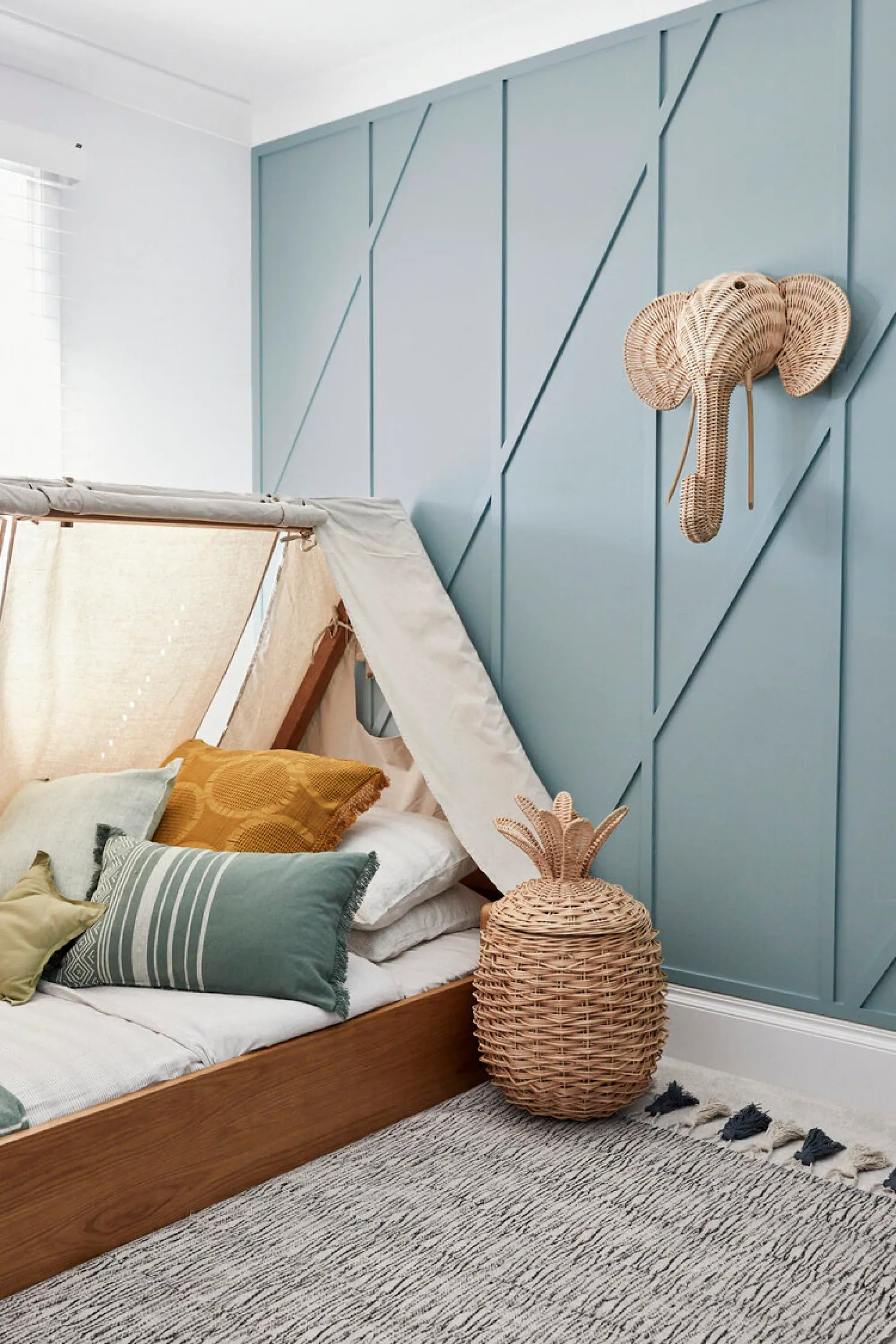 Children's bedroom a tent-like bed and rattan accessories.