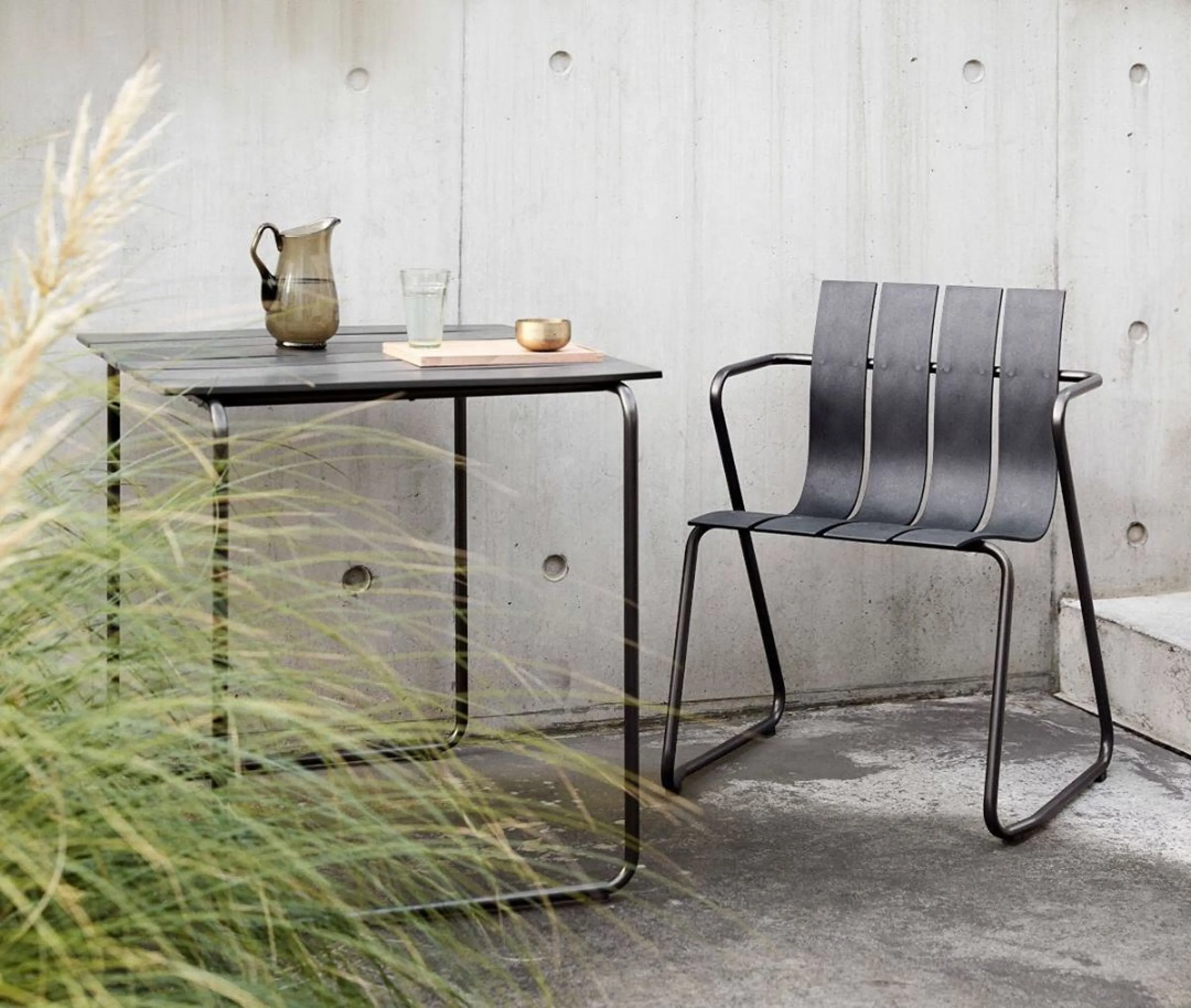 Sustainable plastic chair styled outdoors with a table on the side.