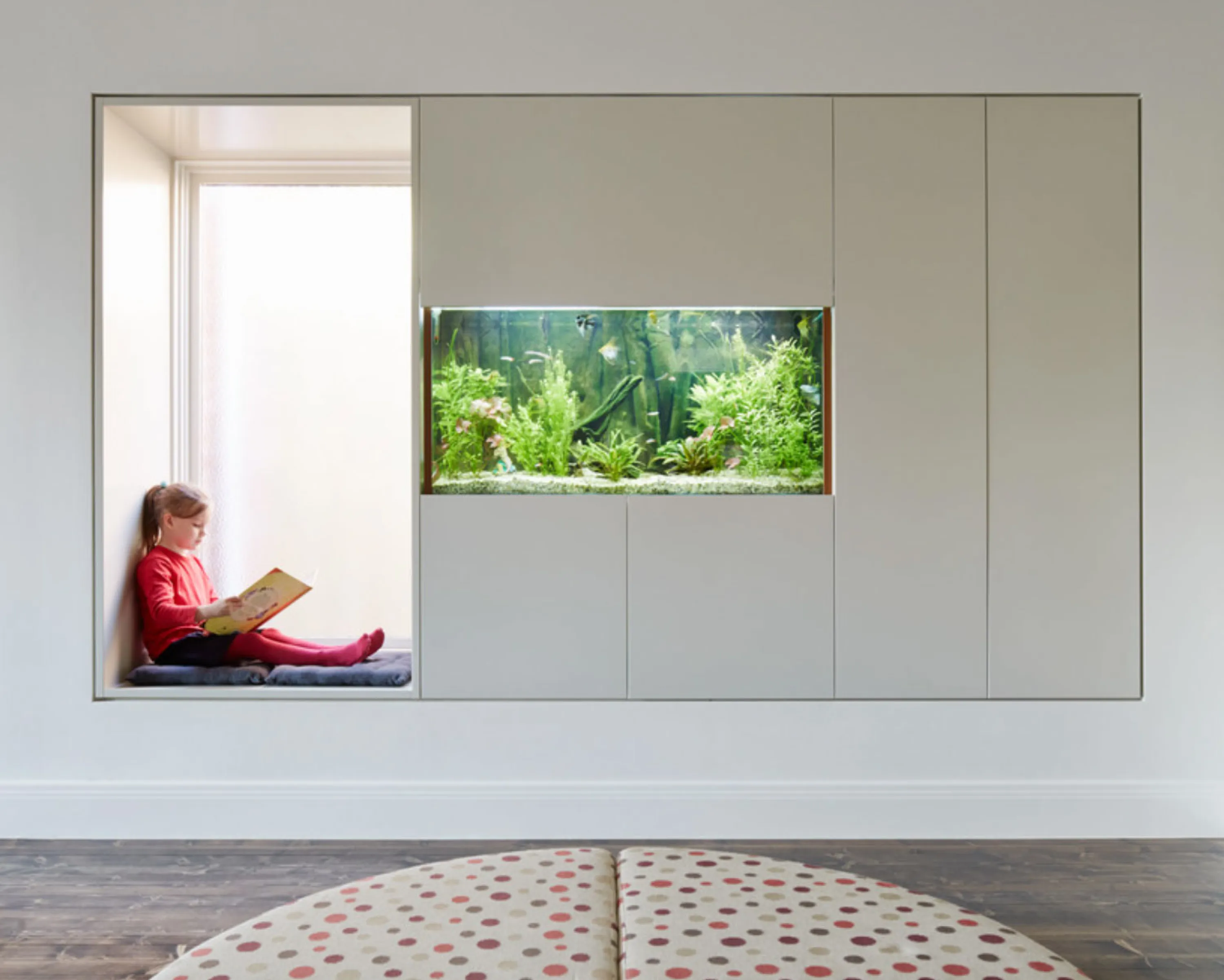 Reading nook in a built-in storage unit that also incorporates an aquarium.