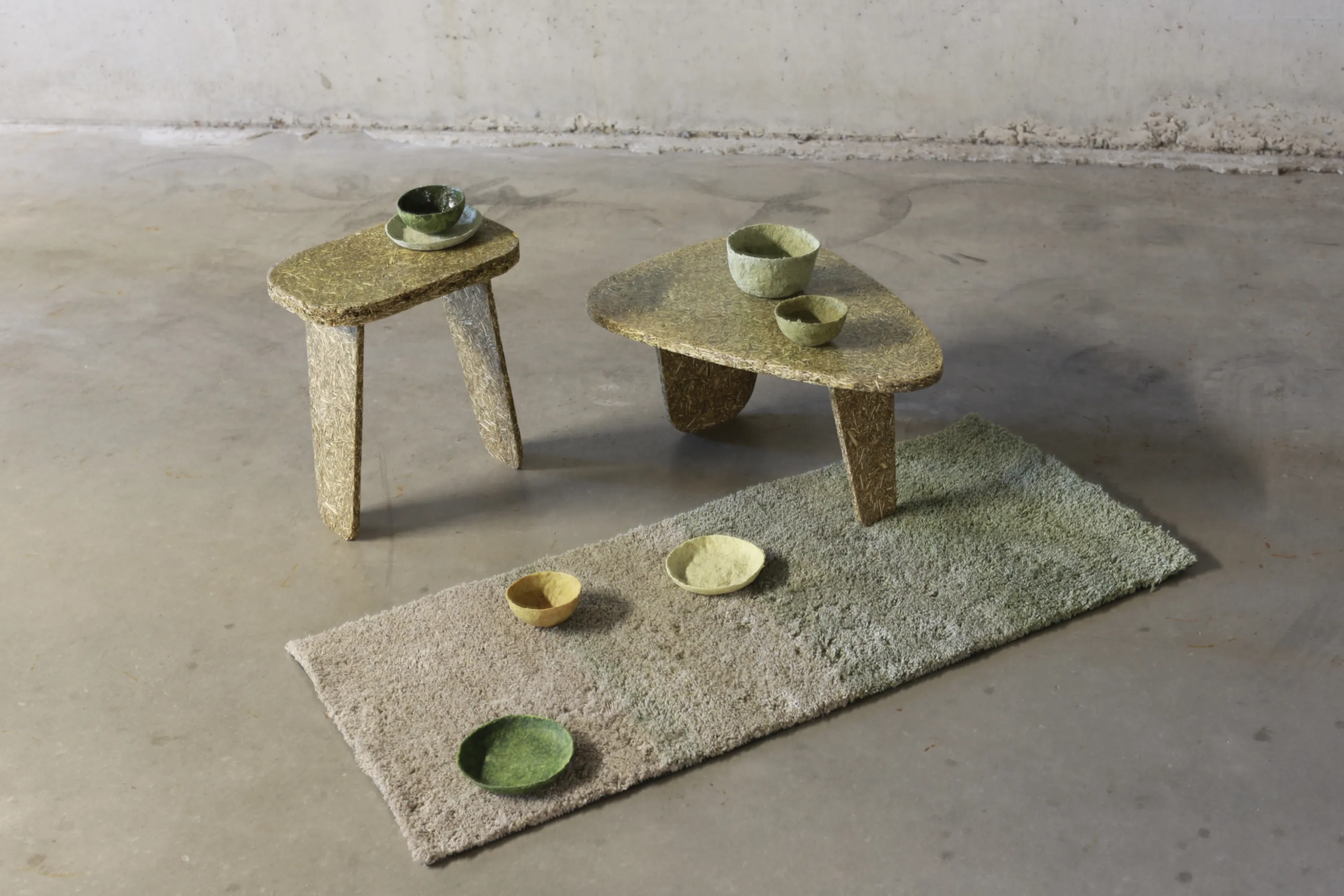 Collection of low tables, bowls and rug made with stinging nettle.