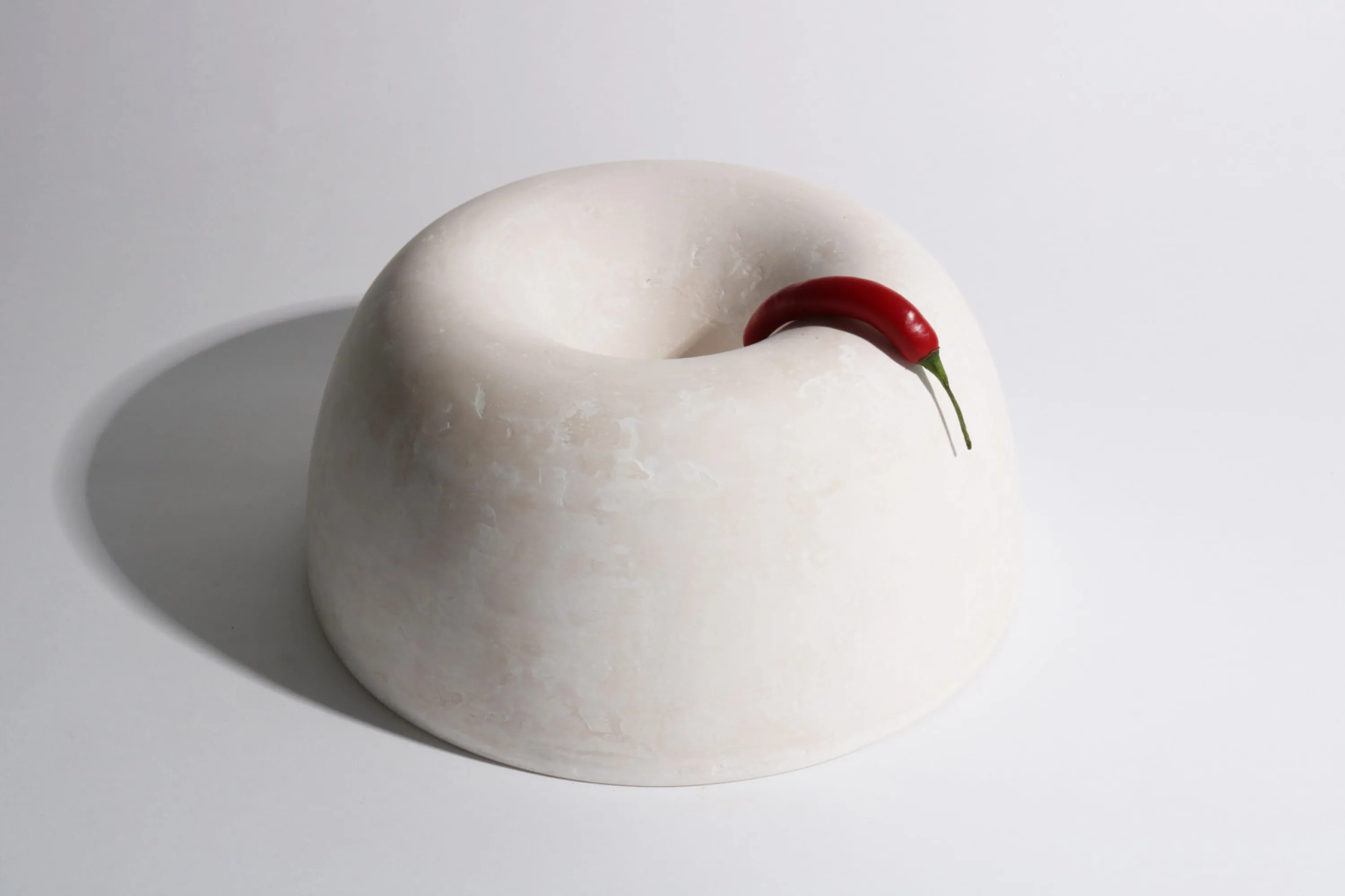 White bowl with a red pepper hanging onto it.