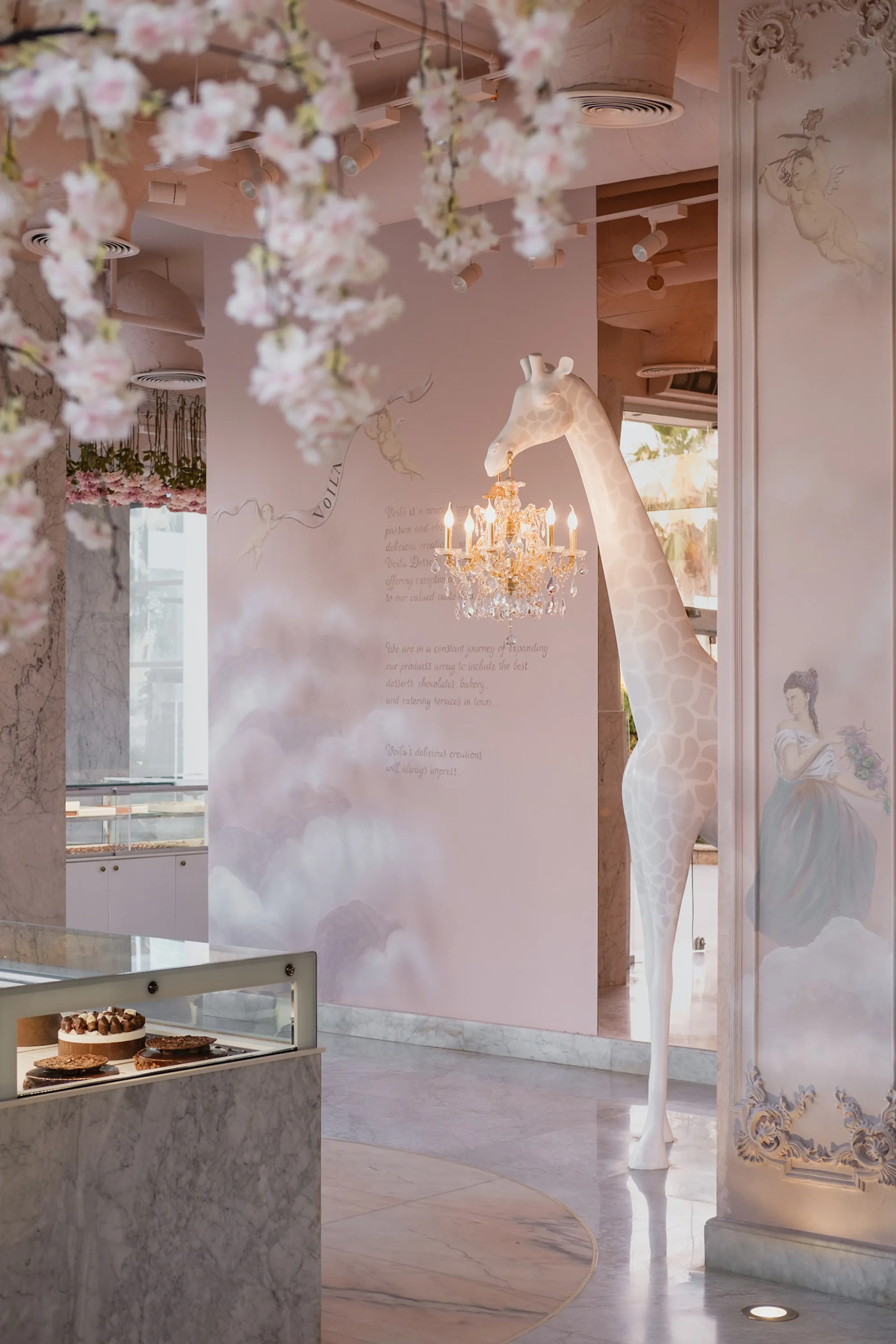 Store interior with flowers hanging from the ceiling and a tall giraffe floor lamp.