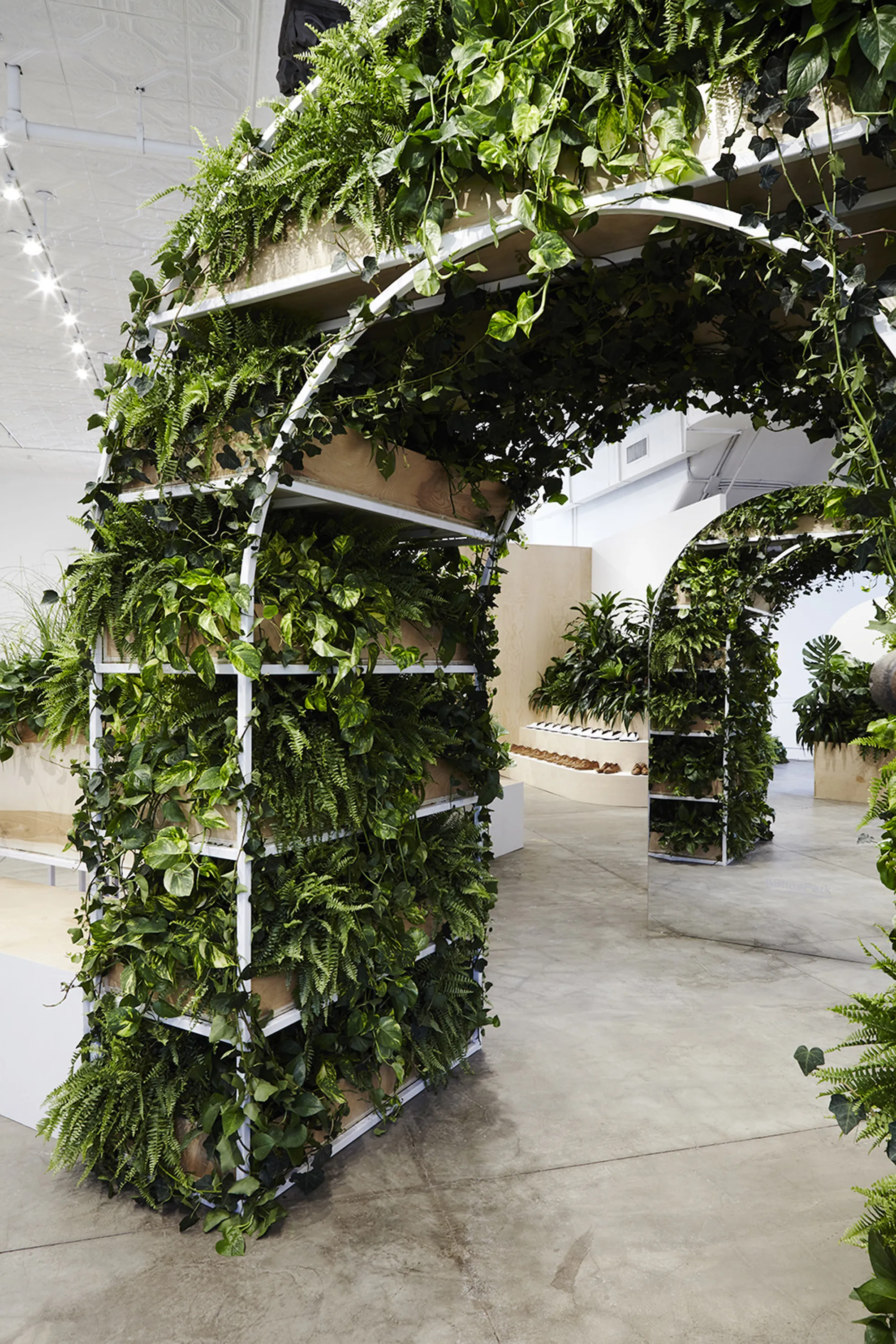 Store with plant-filled arched creating a path in the open space.