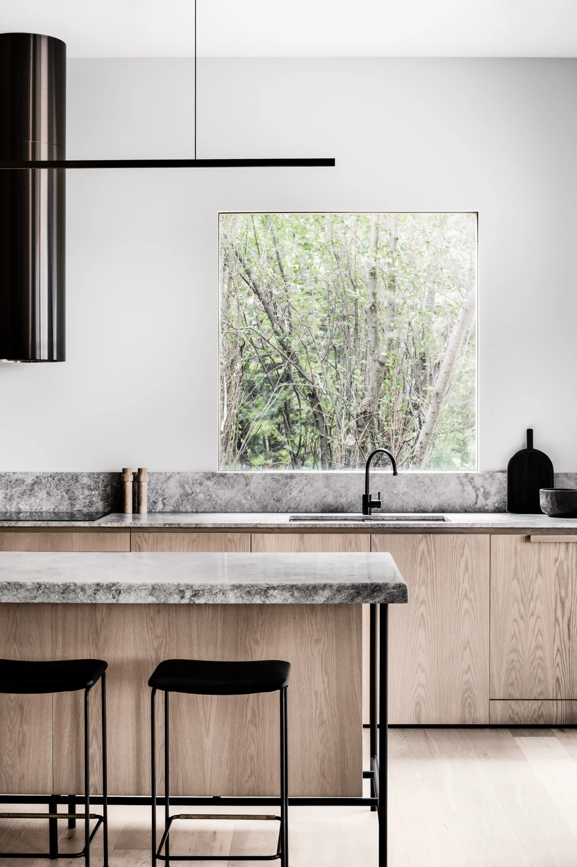 Minimalist kitchen with wood cabinets and stone countertops, great example of biophilic design.