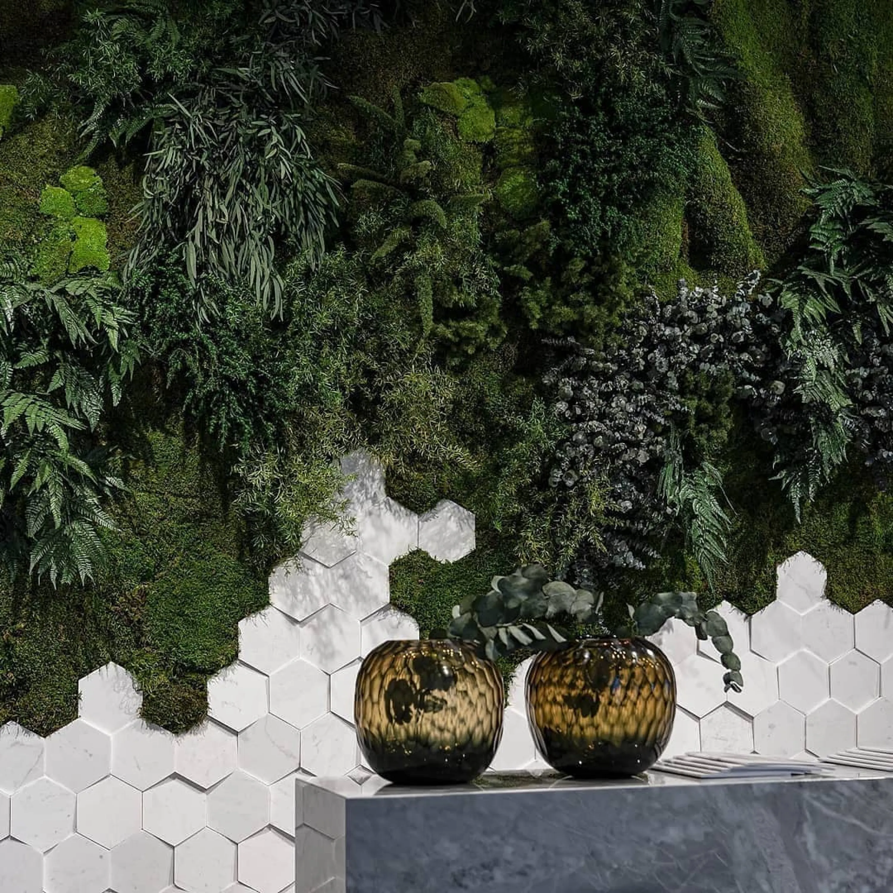 Wall finished with hexagonal tiles on the bottom and a lush vertical garden on the top.