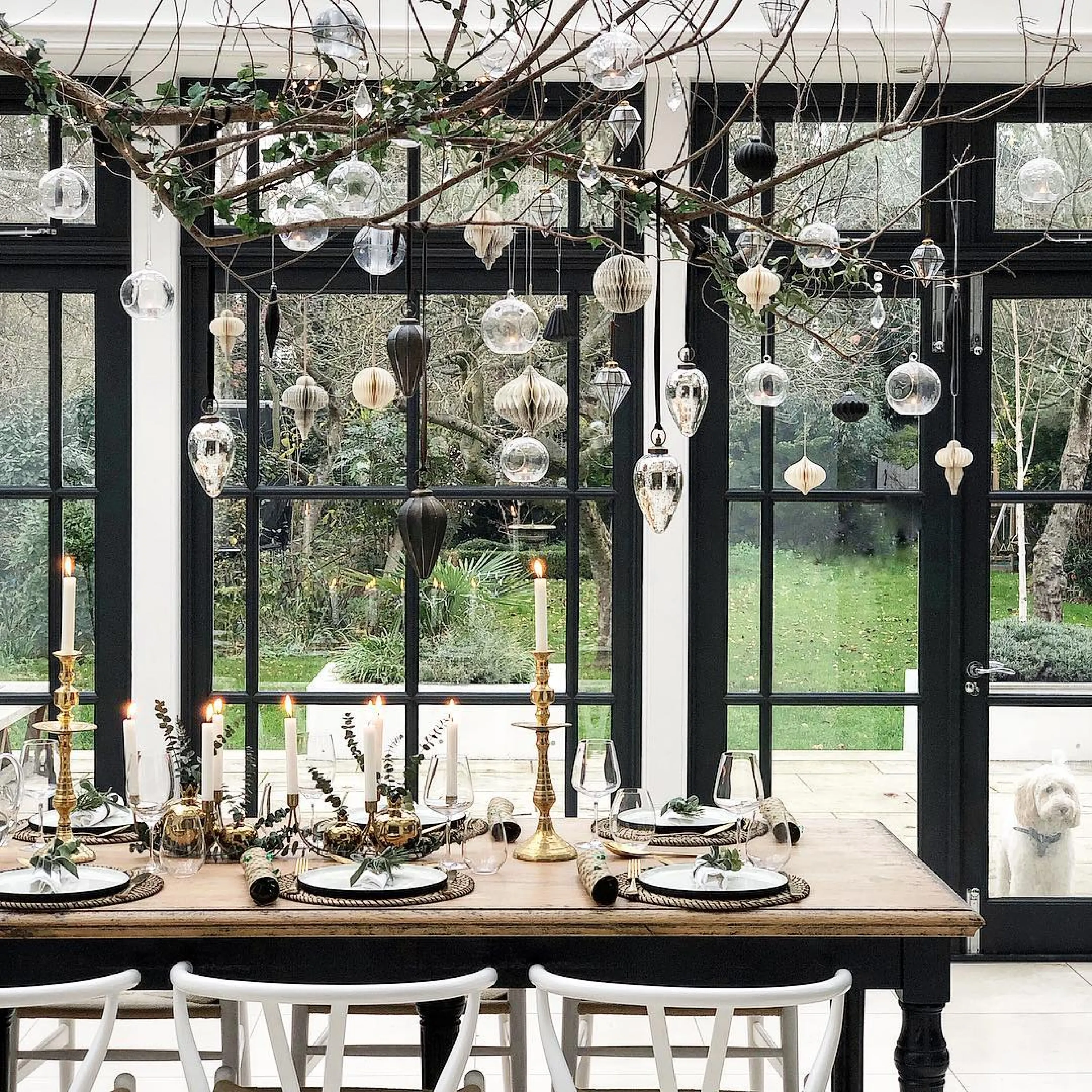 Branch with vintage ornaments hung over a modern dining table.