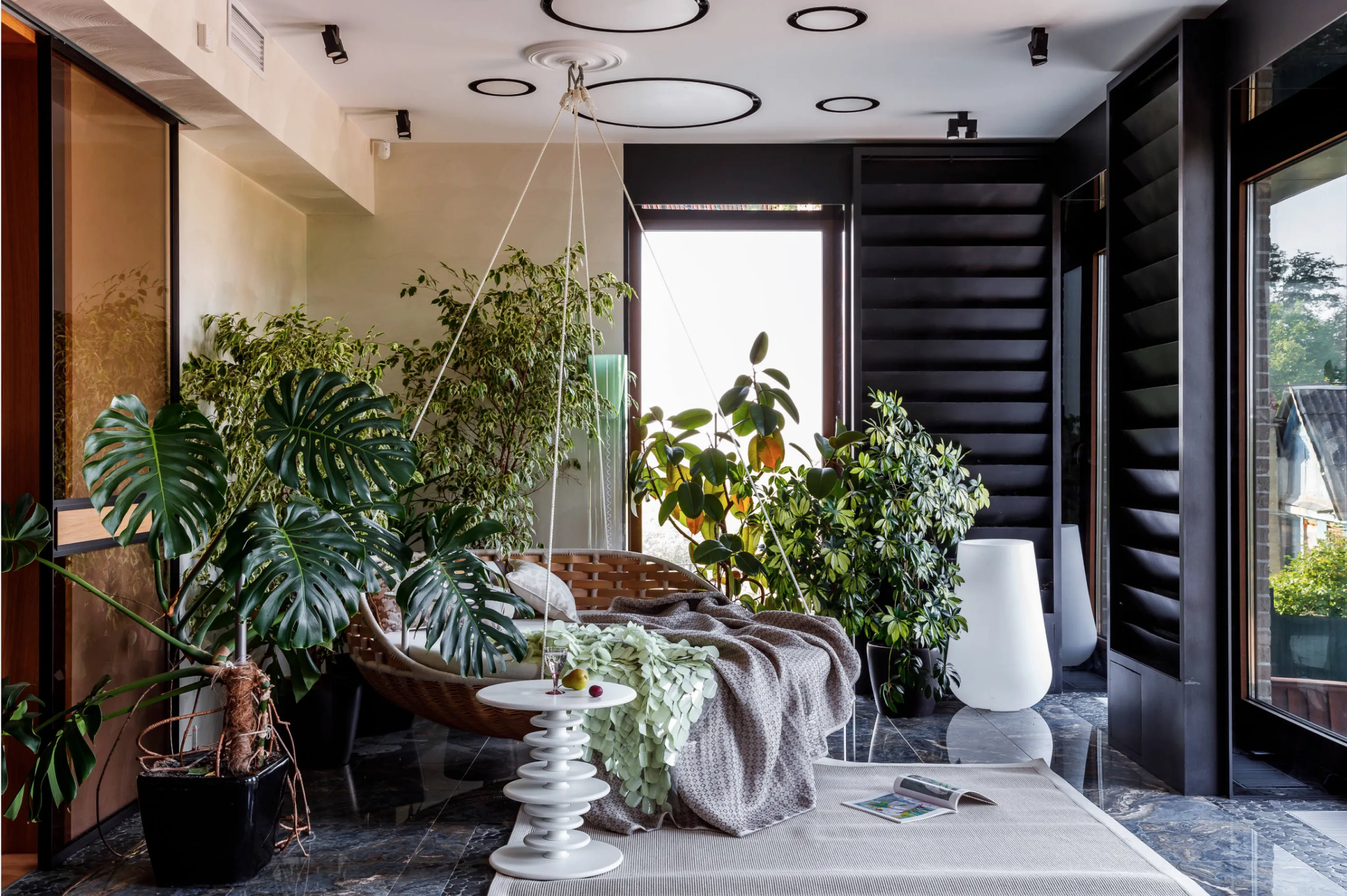 An indoor garden room with hanging sofa.