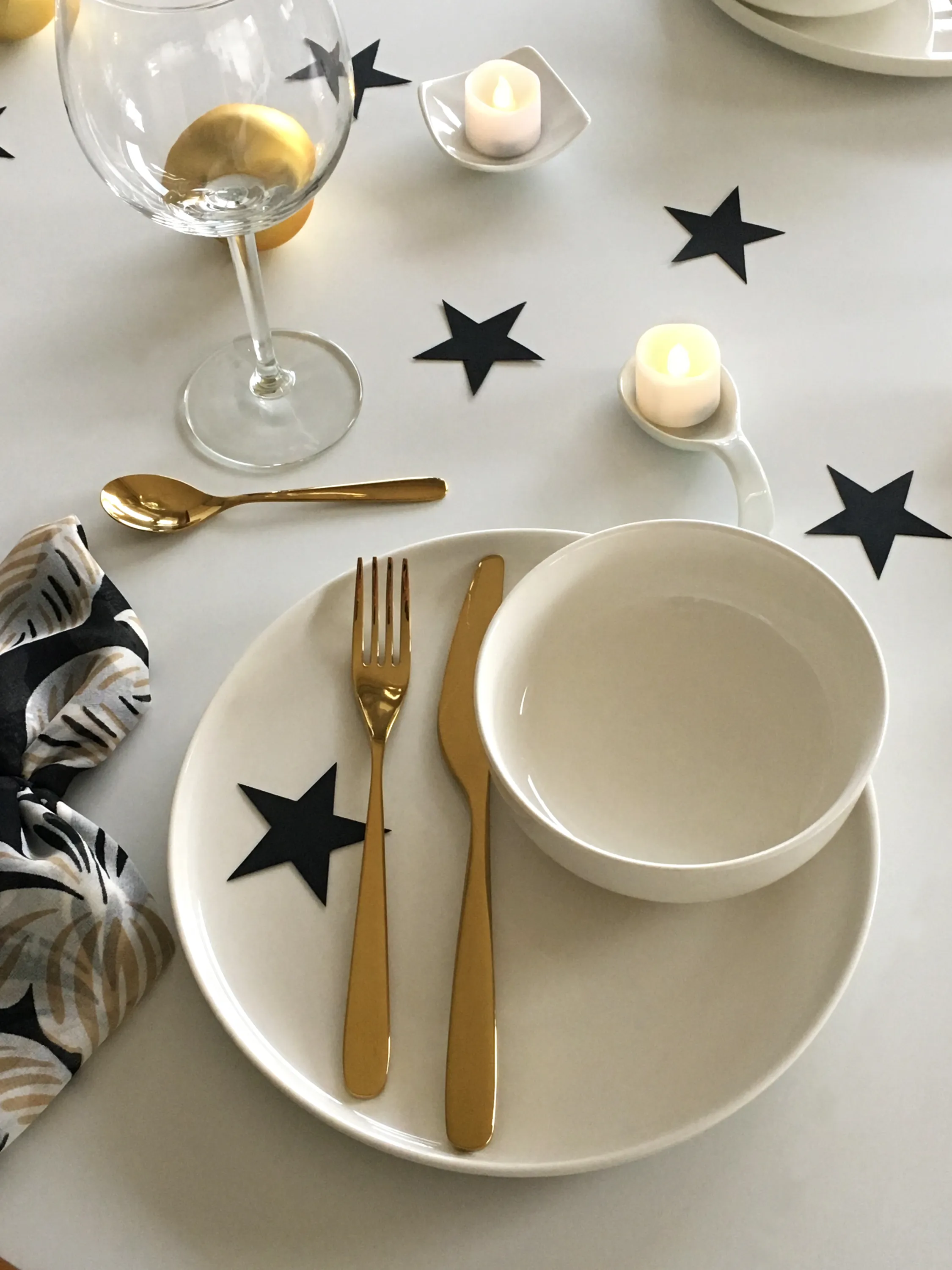 Minimal Christmas table setting with white black cardboard stars and candles as a decor.