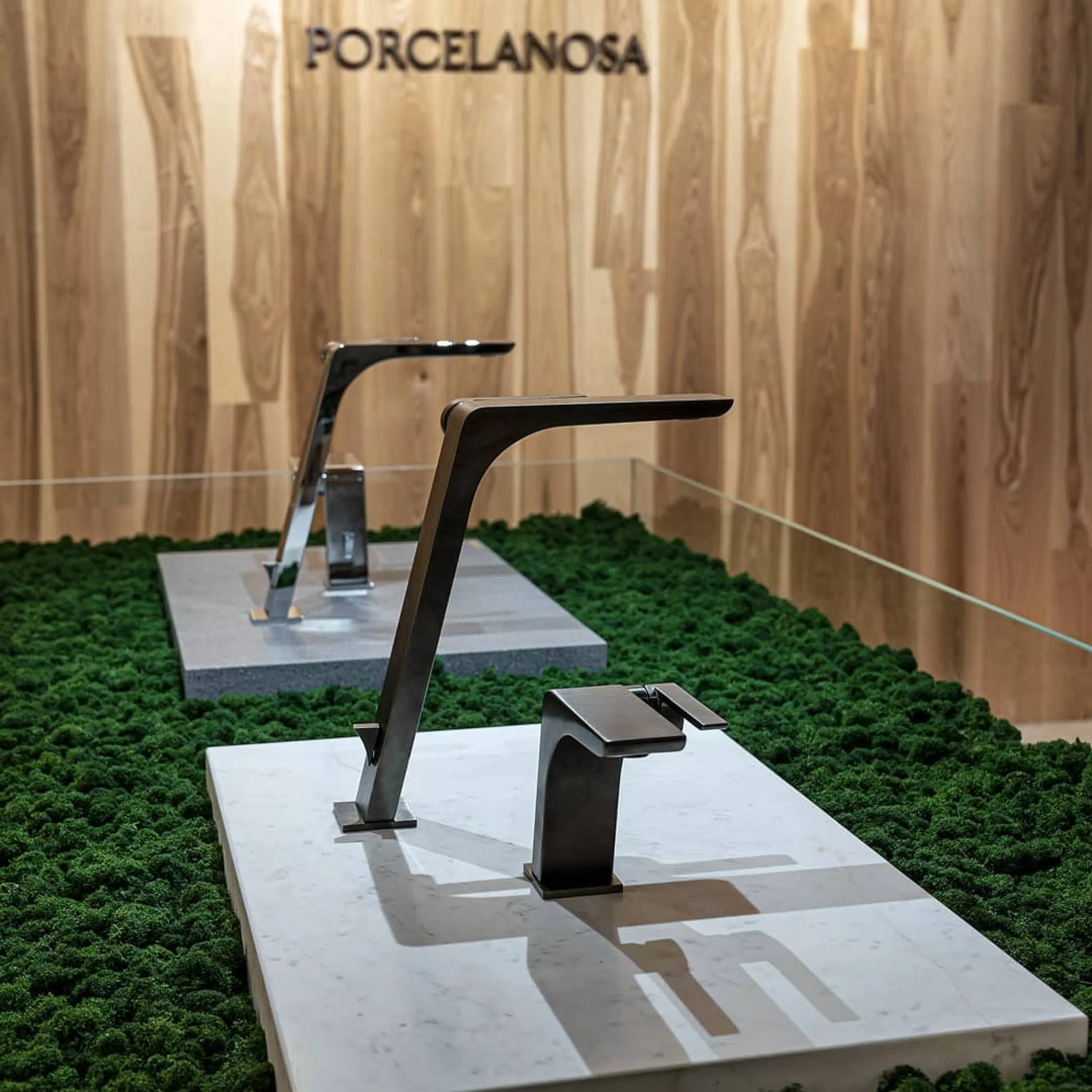 Faucets displayed on a stone slab laid on top of a layer of moss.