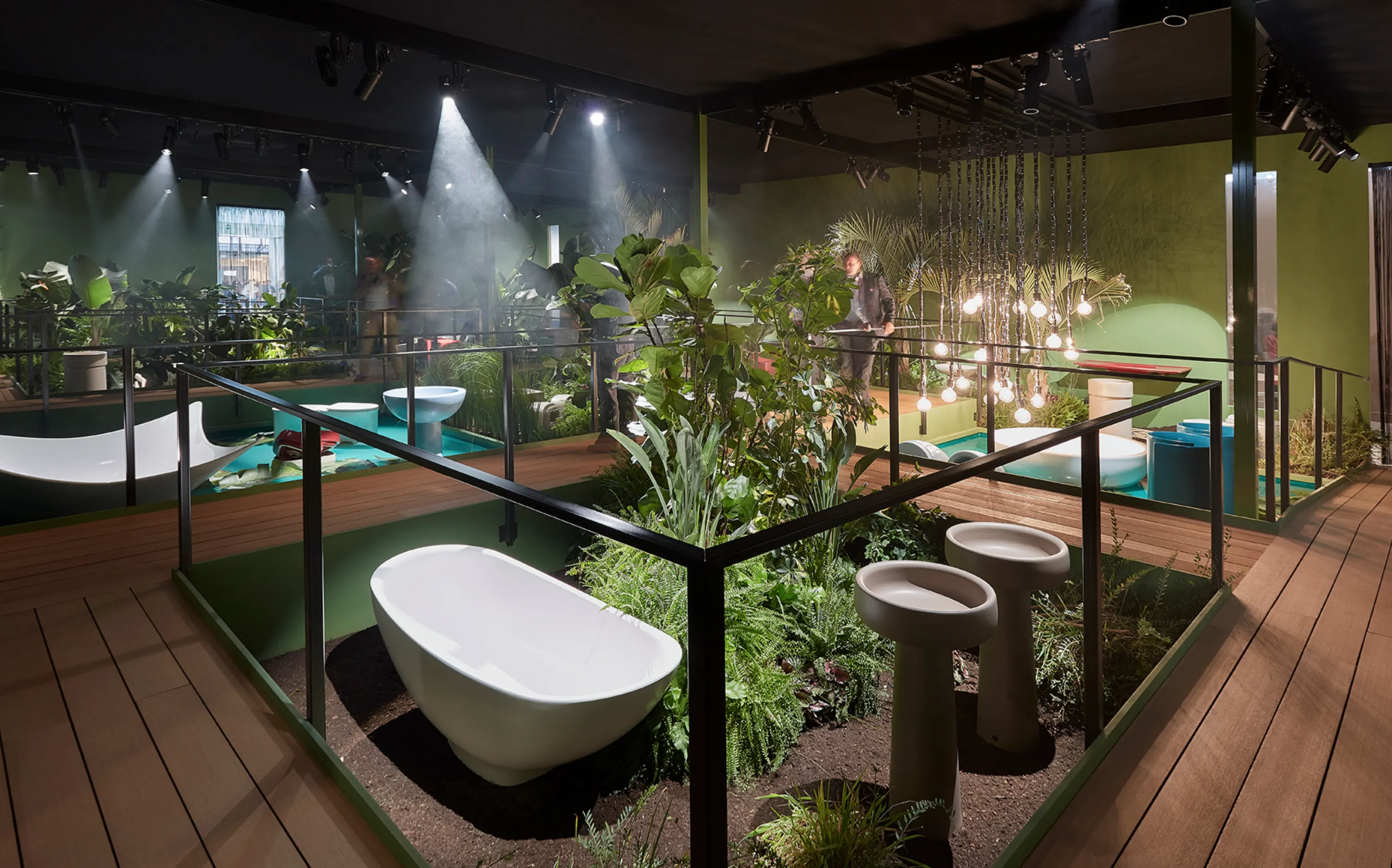 Bathtubs and sinks surrounded by greenery in a jungle oasis inside the booth.