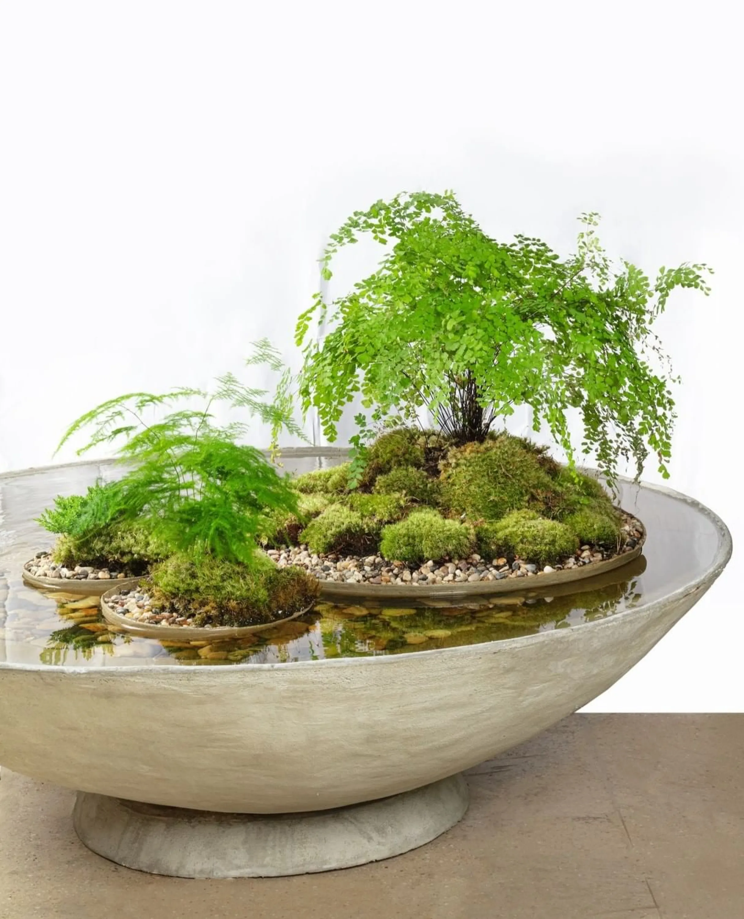 Huge vessel filled with water containing floating smaller vases with plants.