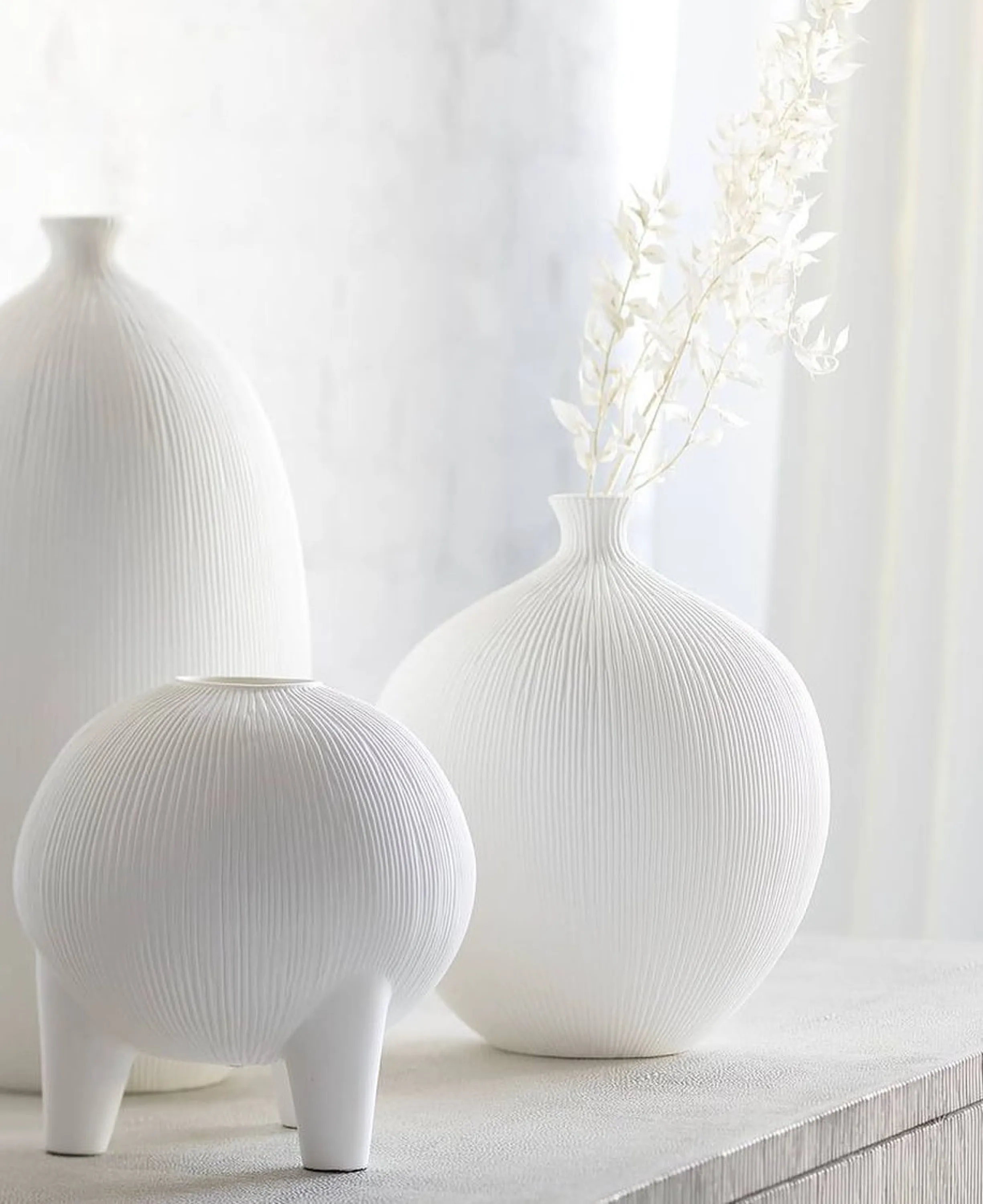 White textured vases containing white stems on a white background.